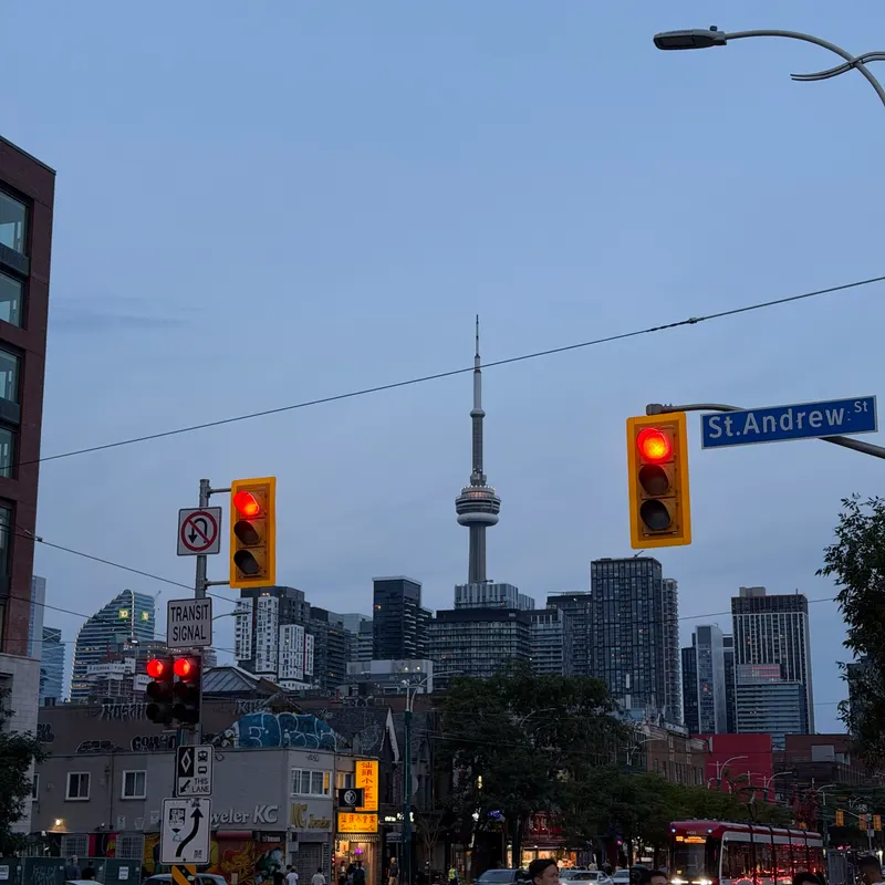 The Toronto skyline and CN Tower at dusk from a street corner