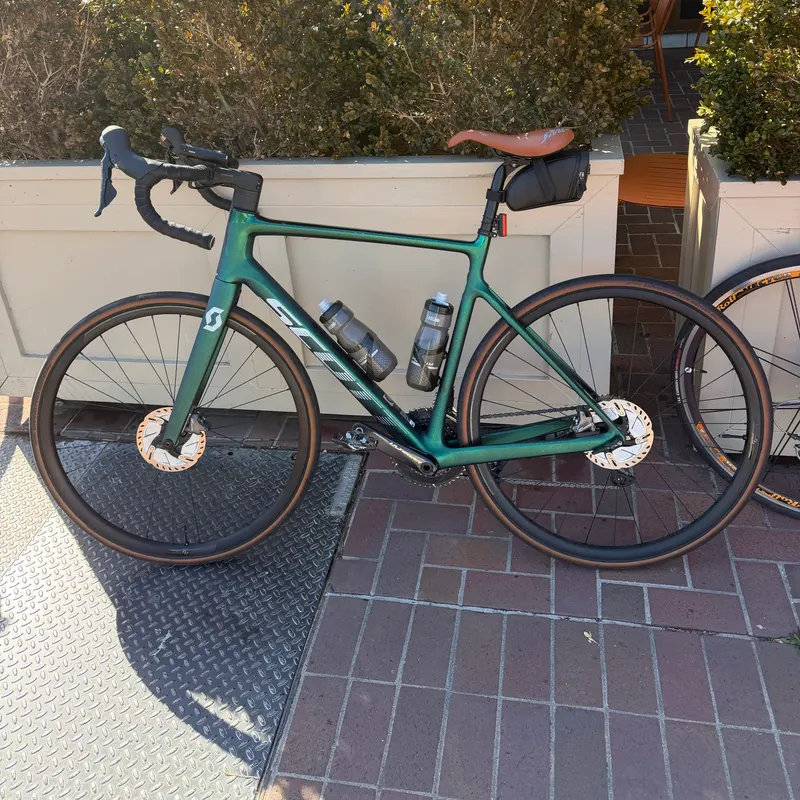 A green road bike leaning against a white wall