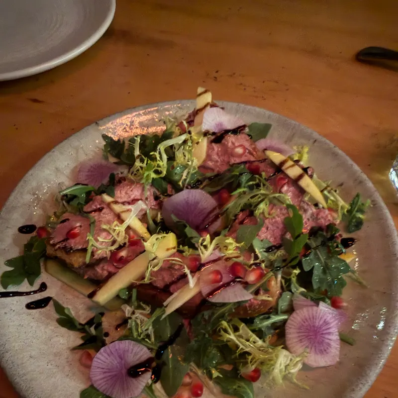 A salad with watermelon radish, greens and pomegranate seeds